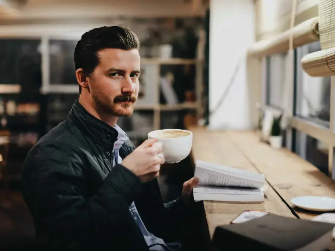 man in black leather jacket holding white ceramic mug